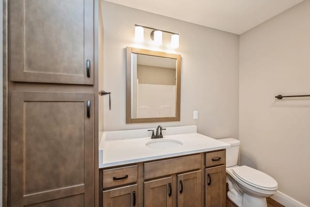 bathroom featuring baseboards, vanity, and toilet