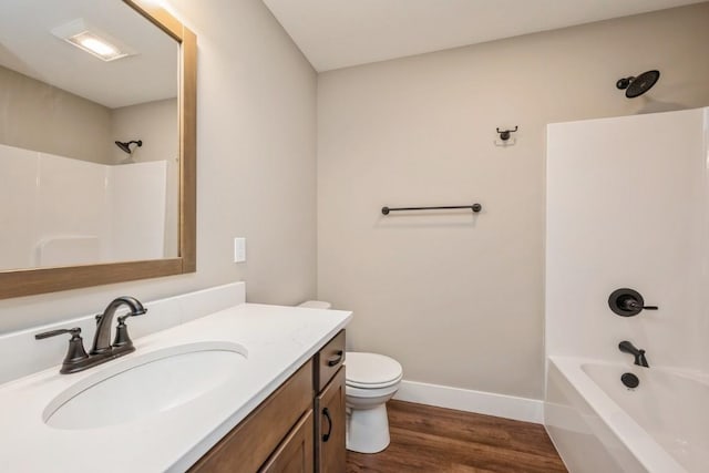 full bath featuring baseboards, toilet, wood finished floors, vanity, and shower / bathing tub combination