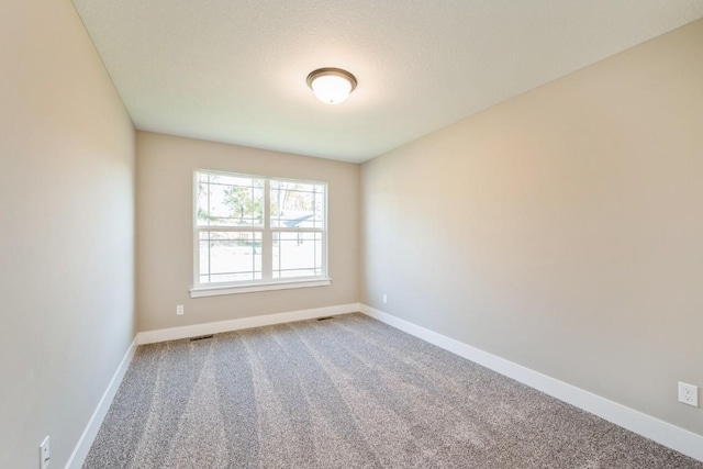 carpeted spare room featuring visible vents and baseboards