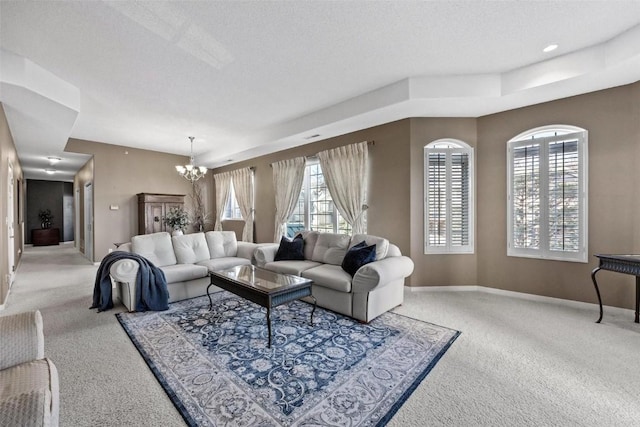 carpeted living room with a wealth of natural light, a textured ceiling, and a notable chandelier