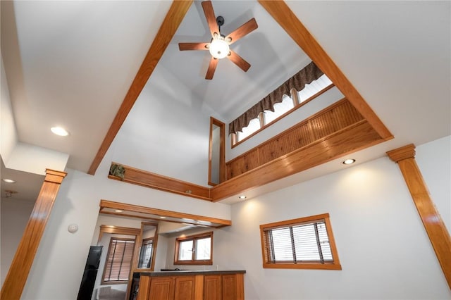 interior space with a towering ceiling, ceiling fan, and ornate columns