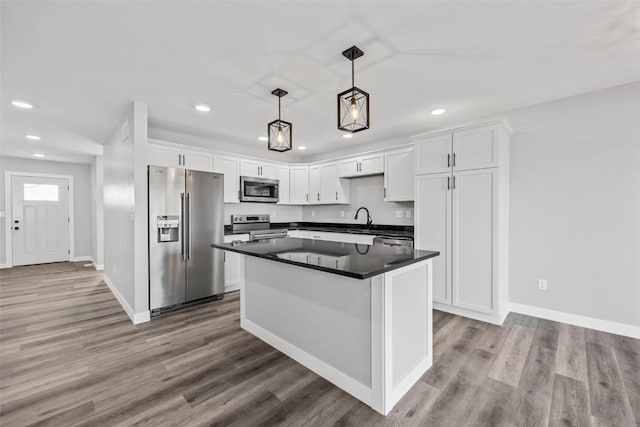 kitchen with white cabinets, sink, hanging light fixtures, light hardwood / wood-style flooring, and stainless steel appliances