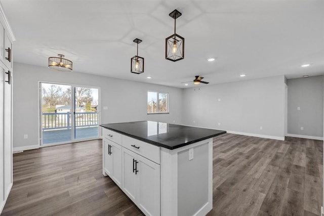 kitchen featuring ceiling fan, hardwood / wood-style floors, a center island, white cabinetry, and hanging light fixtures