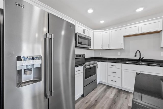 kitchen with sink, light hardwood / wood-style flooring, white cabinets, and appliances with stainless steel finishes