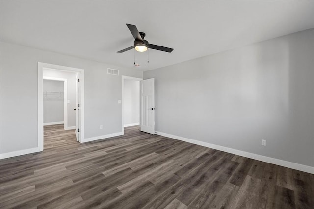 unfurnished bedroom with ceiling fan, a closet, a spacious closet, and dark hardwood / wood-style floors