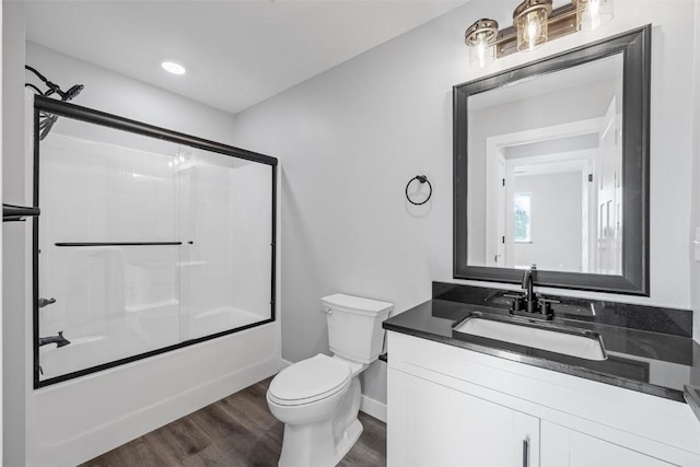 full bathroom featuring vanity, toilet, wood-type flooring, and bath / shower combo with glass door