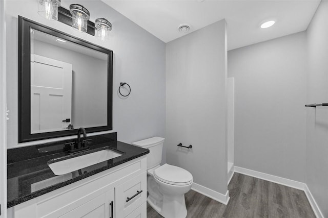 bathroom with a shower, wood-type flooring, vanity, and toilet