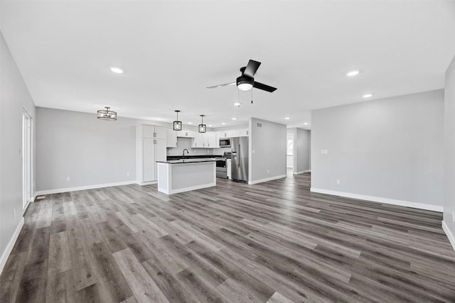 unfurnished living room featuring hardwood / wood-style flooring, ceiling fan, and sink