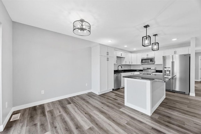 kitchen featuring pendant lighting, sink, light hardwood / wood-style floors, white cabinetry, and stainless steel appliances