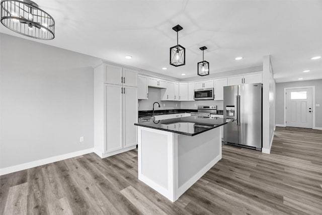 kitchen with pendant lighting, white cabinetry, appliances with stainless steel finishes, and light hardwood / wood-style flooring