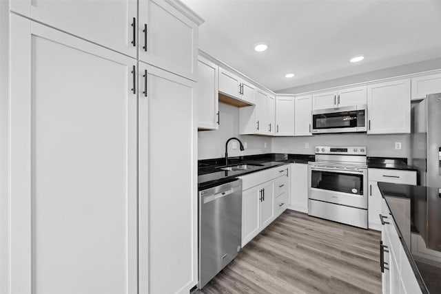 kitchen with white cabinets, light hardwood / wood-style floors, sink, and stainless steel appliances