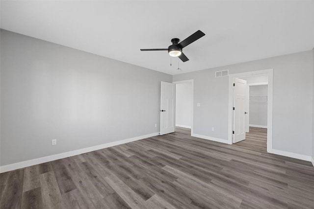 unfurnished bedroom with ceiling fan, dark hardwood / wood-style flooring, a walk in closet, and a closet