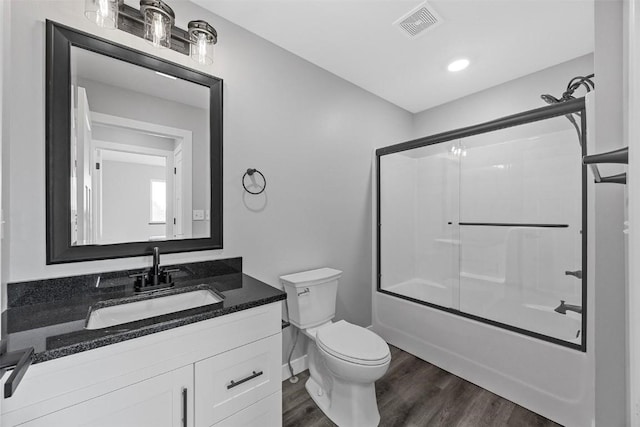 full bathroom with hardwood / wood-style floors, vanity, toilet, and shower / bath combination with glass door