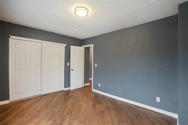 unfurnished bedroom featuring a textured ceiling, dark hardwood / wood-style flooring, and a closet