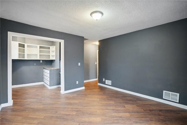 unfurnished room featuring wood-type flooring and a textured ceiling