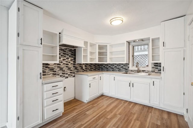 kitchen with white cabinetry, sink, light hardwood / wood-style floors, a textured ceiling, and decorative backsplash