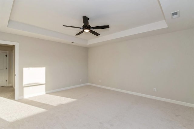 carpeted spare room with ceiling fan and a raised ceiling