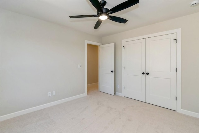 unfurnished bedroom featuring ceiling fan, light colored carpet, and a closet