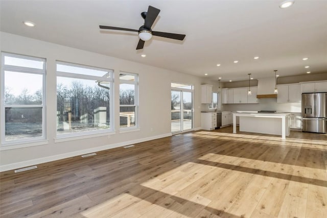 unfurnished living room with light hardwood / wood-style floors, a wealth of natural light, and ceiling fan