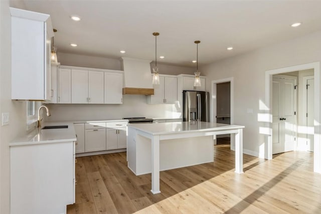 kitchen with premium range hood, stainless steel appliances, decorative light fixtures, white cabinets, and a kitchen island