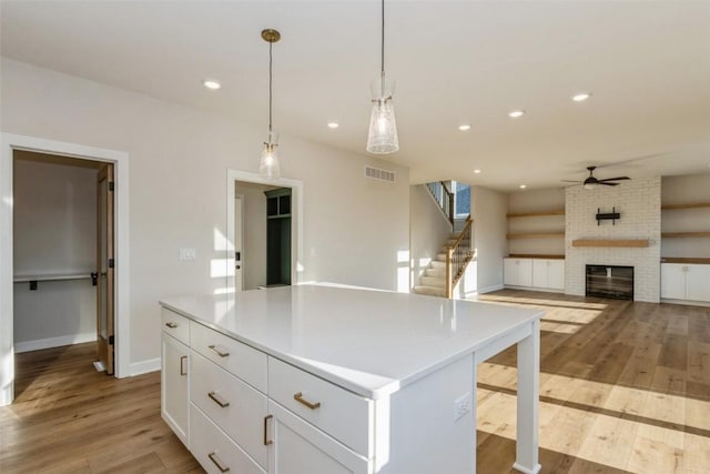 kitchen with ceiling fan, decorative light fixtures, light hardwood / wood-style flooring, a center island, and white cabinetry