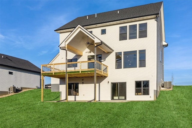 rear view of property featuring a lawn, central air condition unit, and a wooden deck