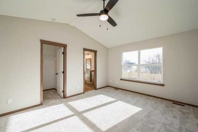 unfurnished bedroom with ceiling fan, a spacious closet, connected bathroom, light colored carpet, and a closet