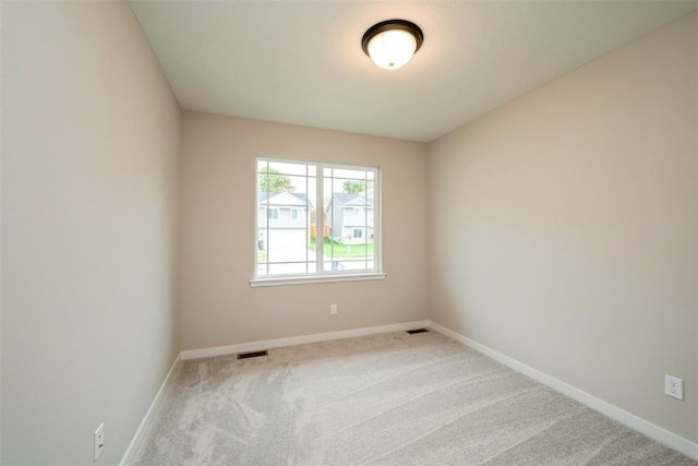 empty room featuring carpet flooring, visible vents, and baseboards