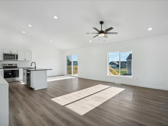 kitchen with white cabinets, dark wood-type flooring, vaulted ceiling, and appliances with stainless steel finishes