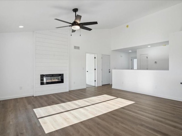 unfurnished living room with a large fireplace, ceiling fan, dark hardwood / wood-style flooring, and high vaulted ceiling