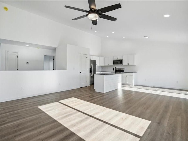 unfurnished living room with dark hardwood / wood-style floors, high vaulted ceiling, and ceiling fan