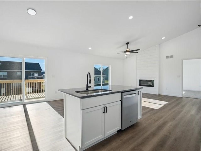 kitchen with white cabinetry, dishwasher, sink, vaulted ceiling, and a kitchen island with sink