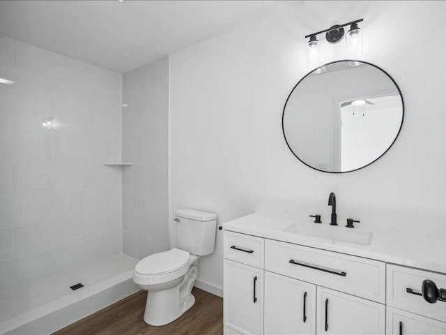 bathroom with tiled shower, wood-type flooring, vanity, and toilet