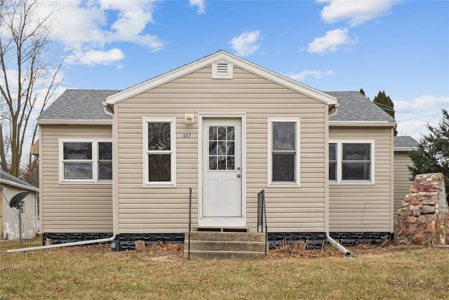 back of property featuring entry steps, a shingled roof, and a lawn