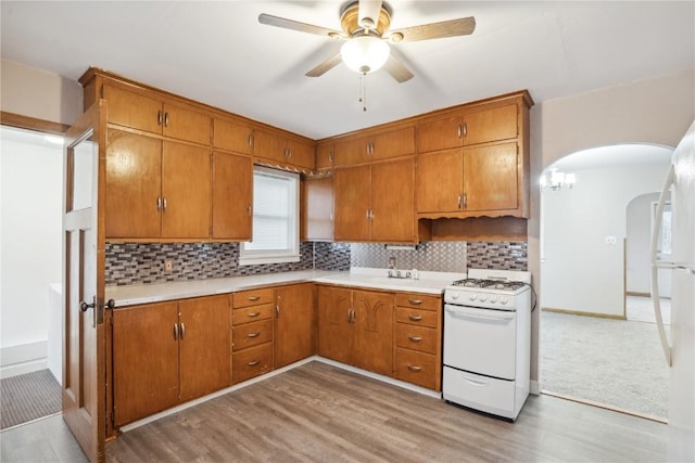 kitchen with white appliances, brown cabinets, and backsplash