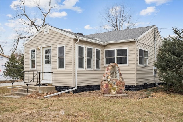 exterior space featuring a shingled roof, entry steps, and a lawn