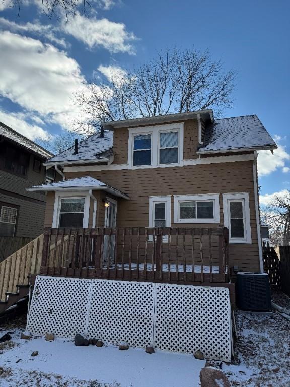 snow covered property with cooling unit and a wooden deck