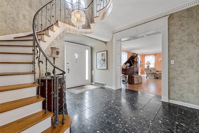 entryway featuring plenty of natural light, dark hardwood / wood-style floors, ornamental molding, and an inviting chandelier