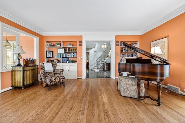 sitting room with built in shelves, light hardwood / wood-style floors, and ornamental molding