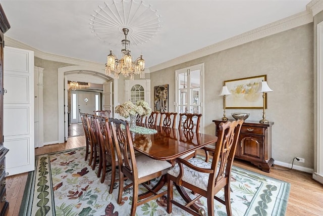 dining area featuring crown molding, a healthy amount of sunlight, a notable chandelier, and light wood-type flooring