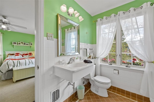 bathroom with toilet, tile walls, and ceiling fan