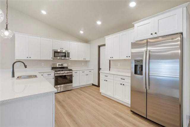 kitchen featuring stainless steel appliances, vaulted ceiling, white cabinetry, and a sink