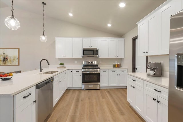 kitchen with a peninsula, lofted ceiling, light countertops, a sink, and stainless steel appliances