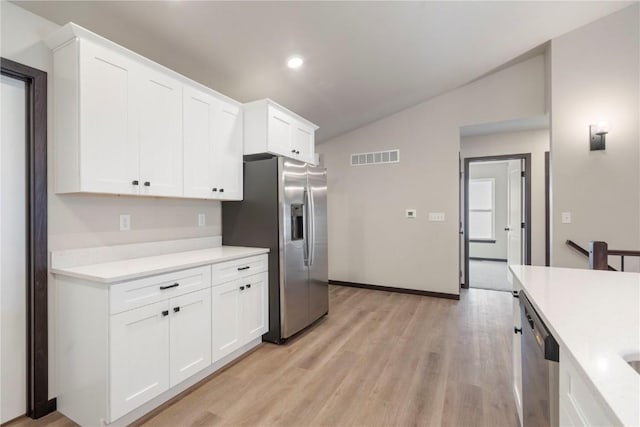 kitchen with visible vents, light countertops, light wood finished floors, vaulted ceiling, and stainless steel appliances