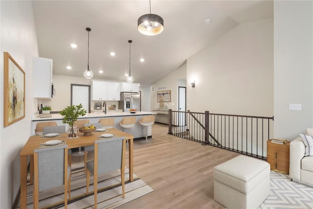 kitchen featuring light countertops, stainless steel fridge with ice dispenser, high vaulted ceiling, light wood finished floors, and white cabinetry