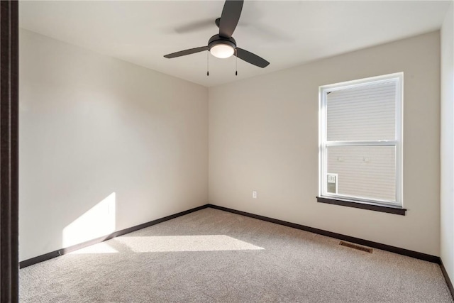 carpeted spare room featuring a ceiling fan, baseboards, and visible vents