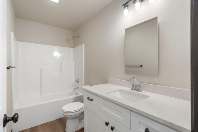 bathroom with toilet, wood finished floors, shower / bathing tub combination, and vanity