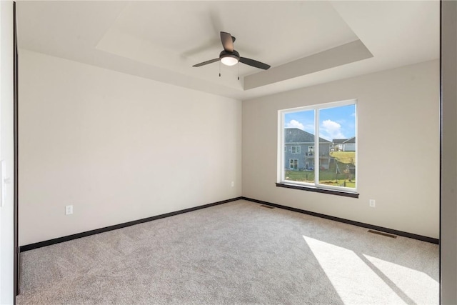 spare room featuring a raised ceiling, baseboards, and carpet floors