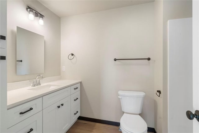 bathroom with vanity, baseboards, wood finished floors, and toilet
