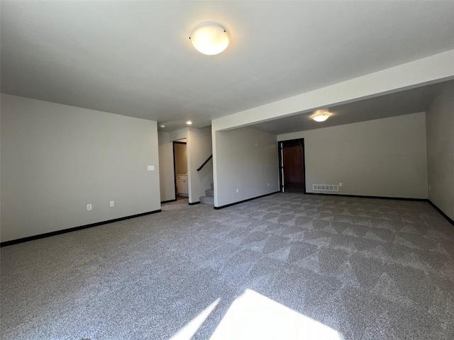 carpeted spare room featuring visible vents, baseboards, and stairway
